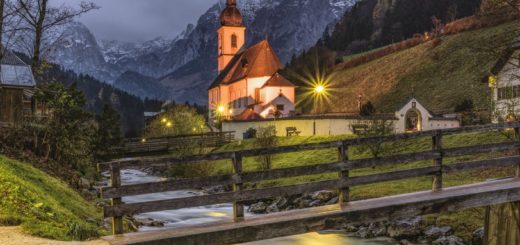 Serene mountain village with church and river at dusk, picturesque scenery, and peaceful atmosphere.