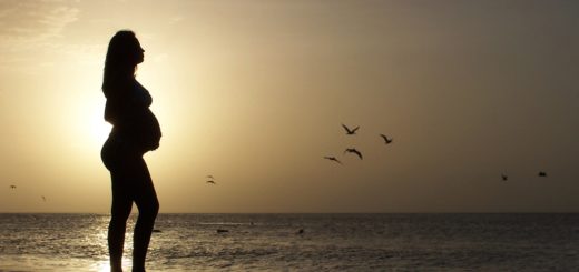 Pregnant woman silhouette on the beach at sunset, symbolizing hope and new beginnings.