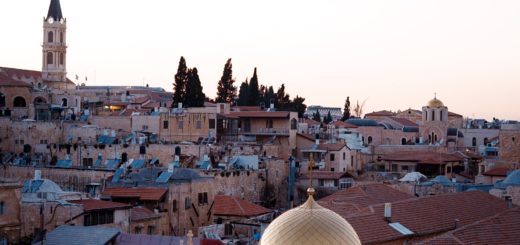 Ancient Jerusalem skyline with golden-domed church and historic stone buildings at sunset.