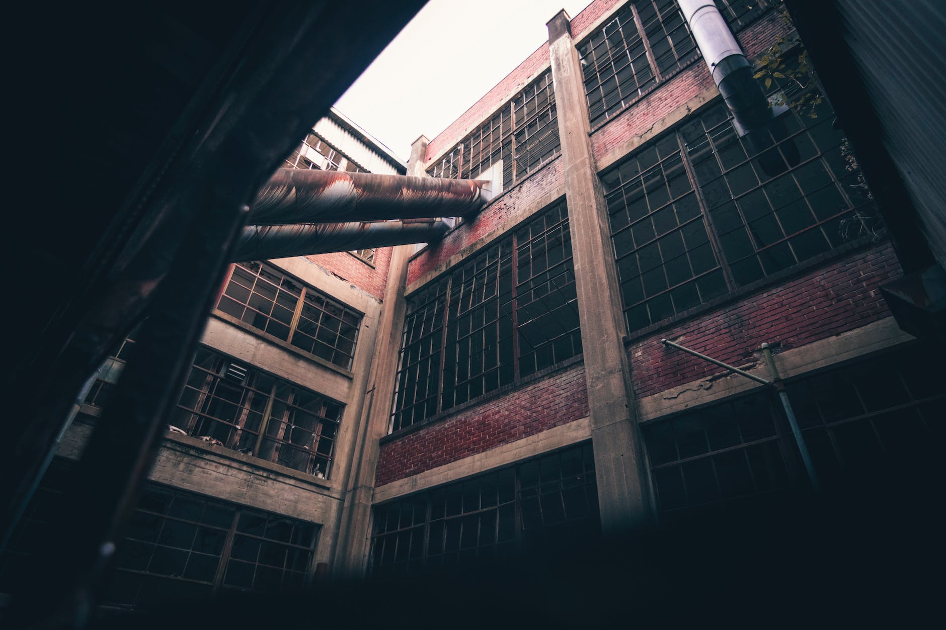 Abandoned industrial building with large windows and exposed brick walls, urban decay scene.